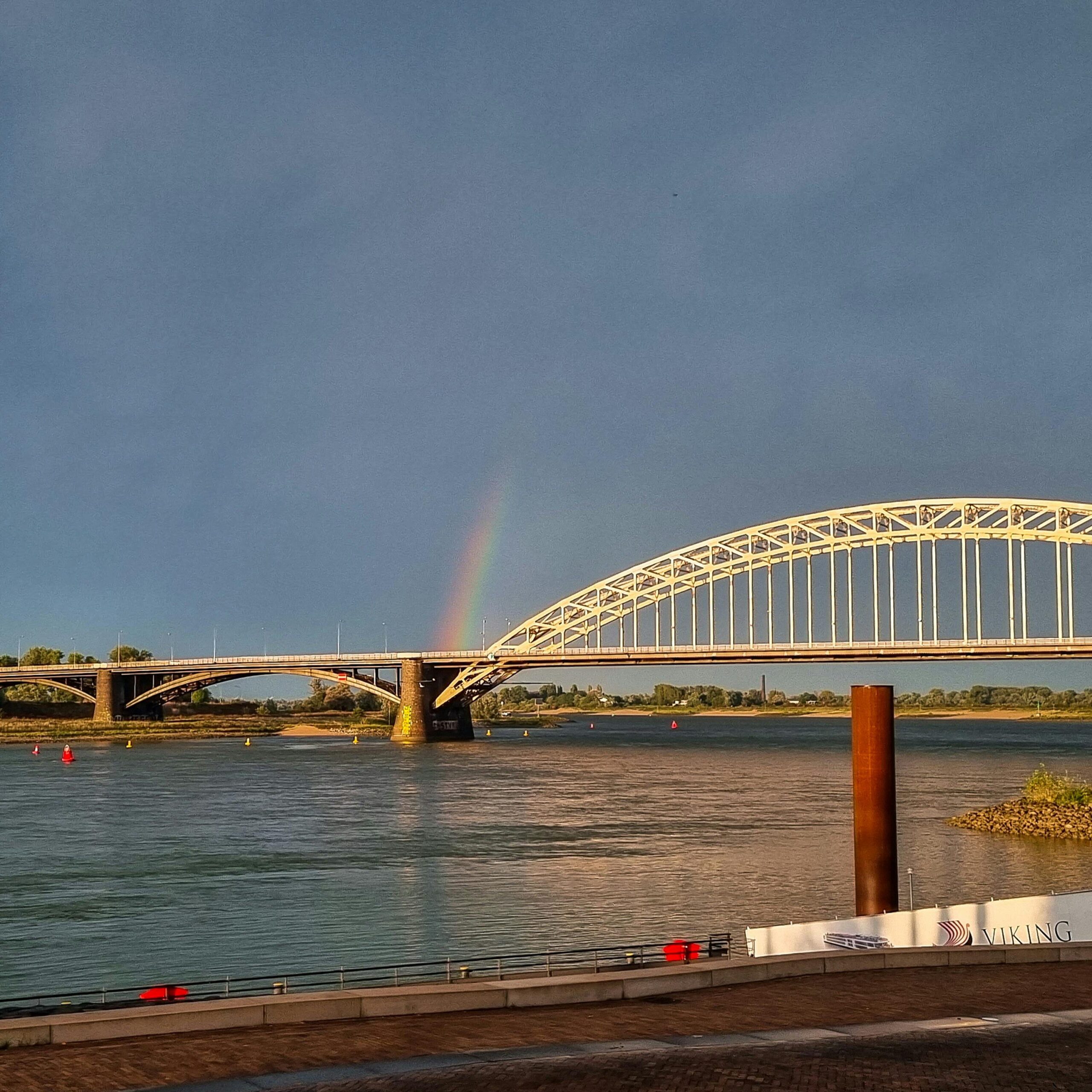 Picturesque view of Nijmegen bridge with a rainbow over the river in the Netherlands.